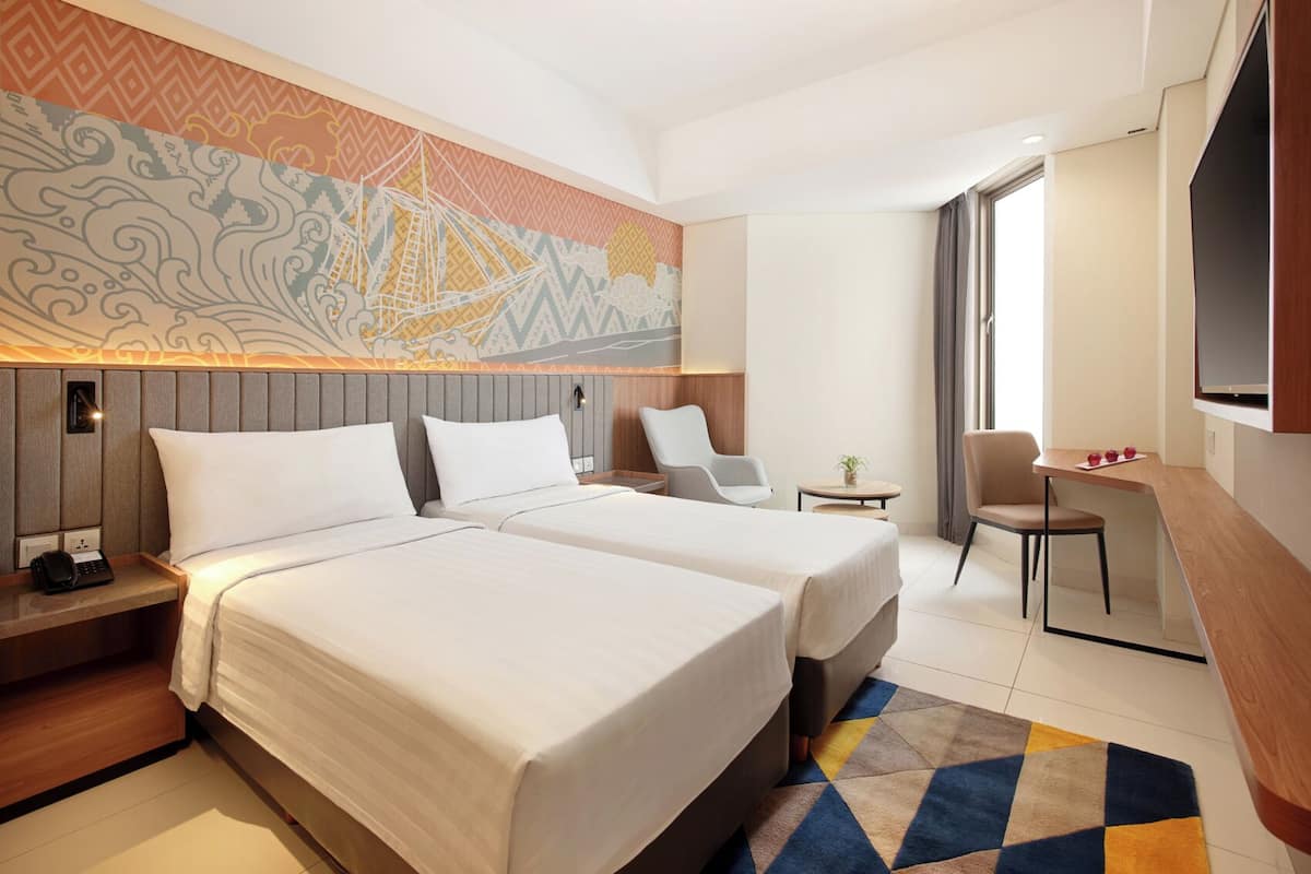 Een hotelkamer met twee bedden, een bureau, een stoel en een televisie.
