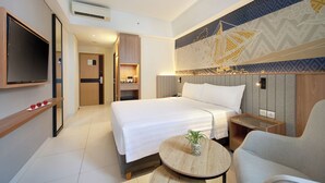 A hotel room with a bed, bedside table, TV, and a decorative wall.
