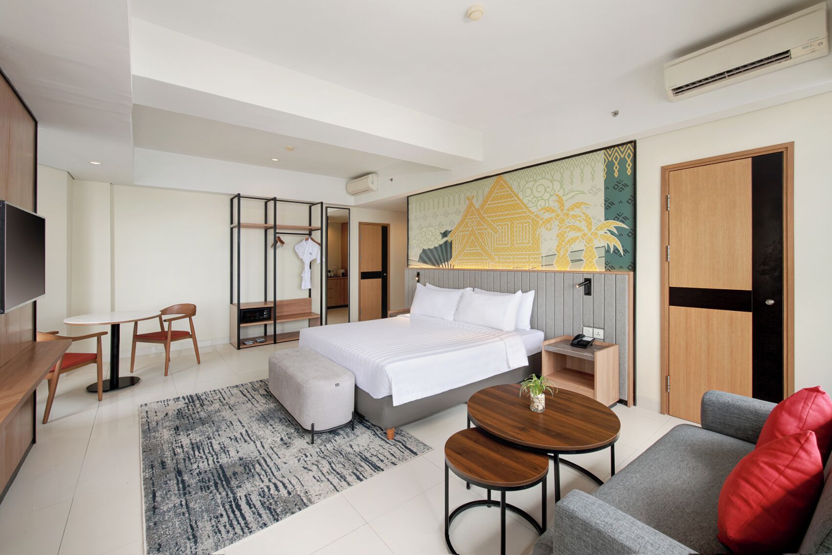 Ein modernes Hotelzimmer mit Bett, Schreibtisch, Sofa und einem kleinen Tisch.