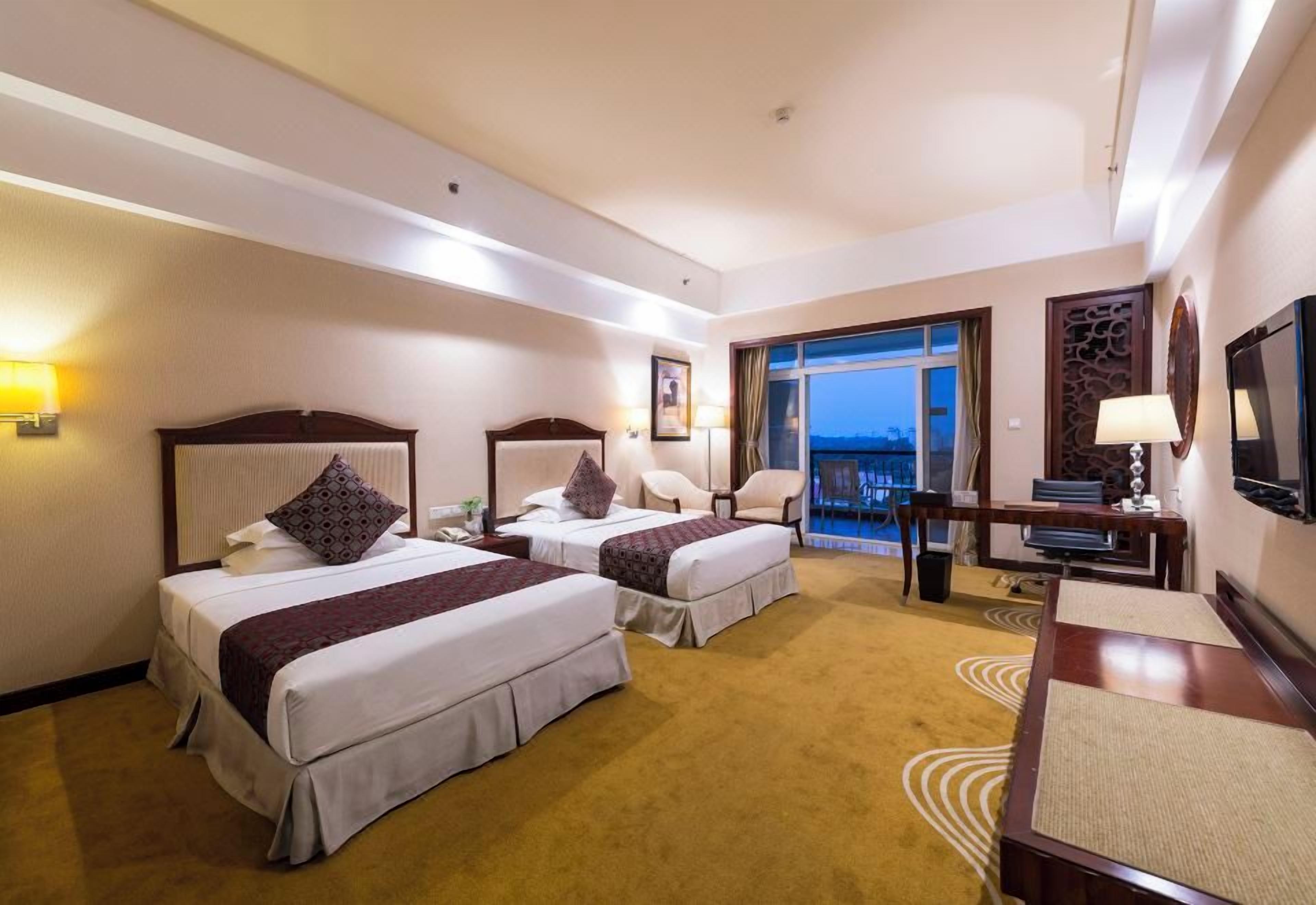 Ett hotellrum med två sängar, ett skrivbord, en stol, en TV och utsikt över omgivningarna.