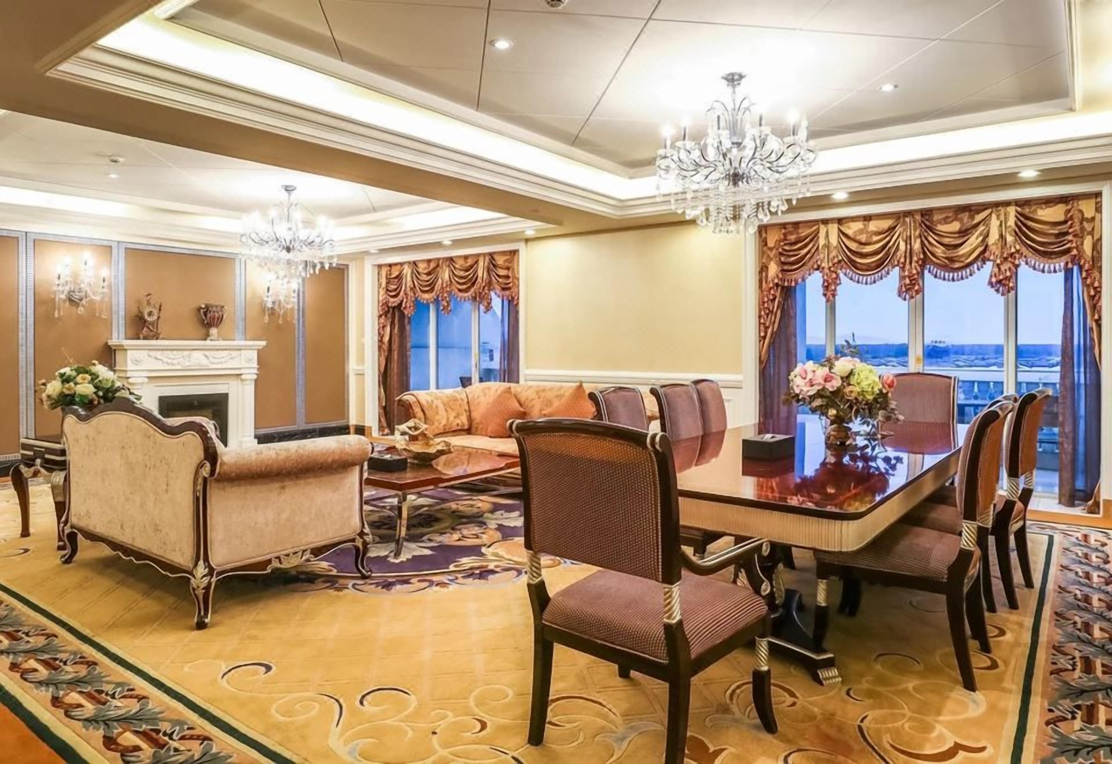 A hotel room with a dining area, a fireplace, and a view of the cityscape.