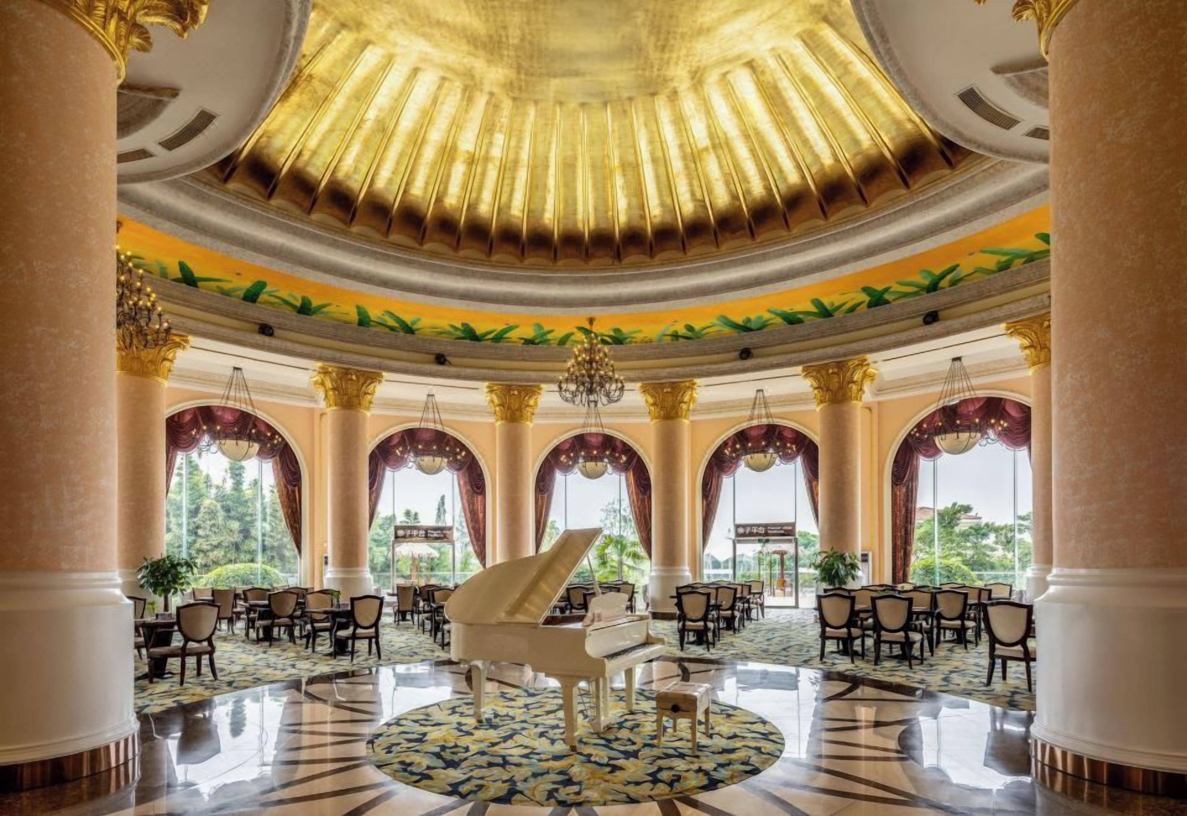 A grand lobby with a grand piano, multiple seating areas, and large windows.