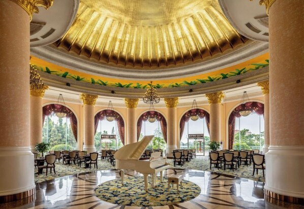 A grand lobby with a grand piano, multiple seating areas, and large windows.