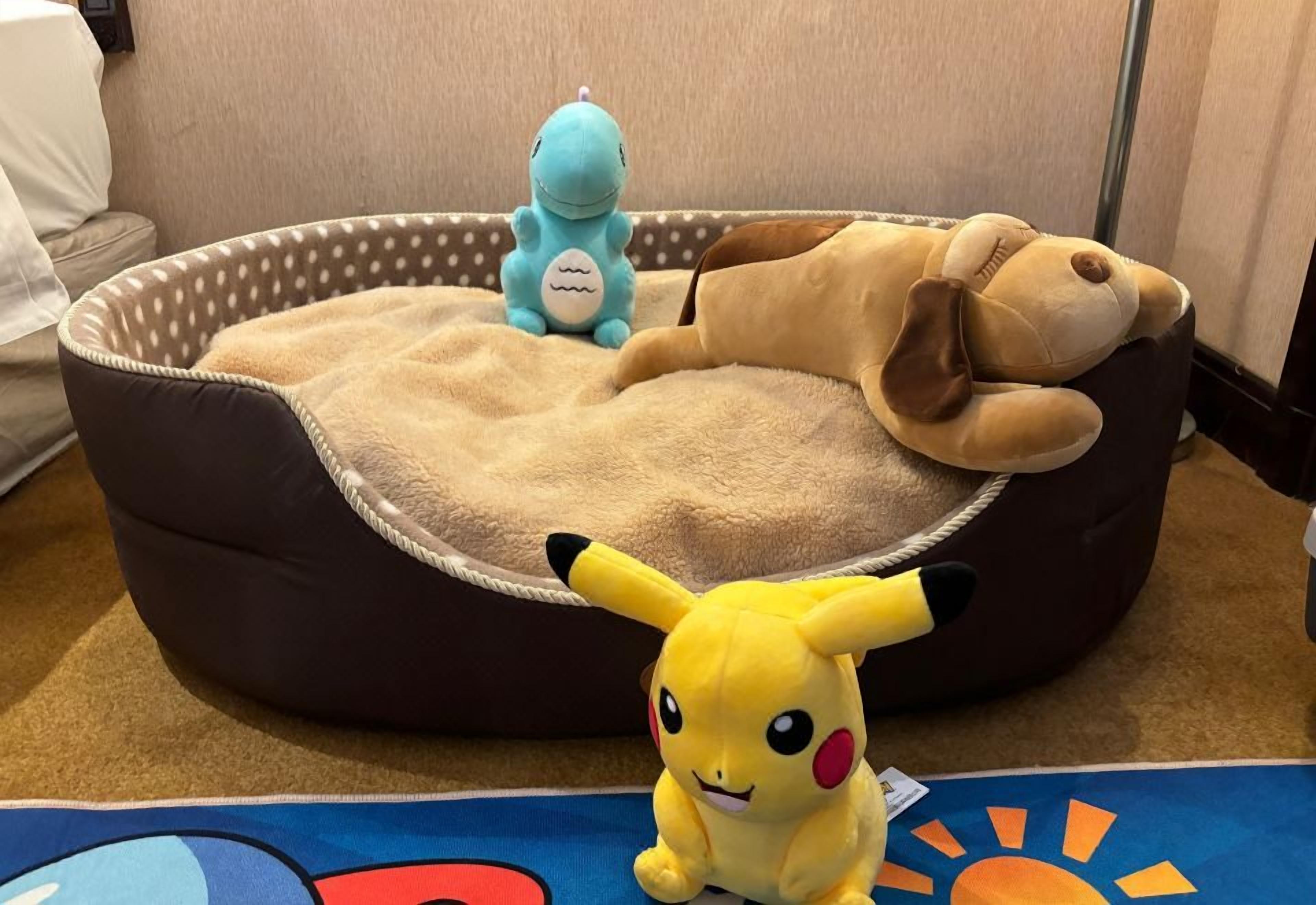 A plush toy bed with a polka-dotted edge, a stuffed animal, and a small Pikachu toy.