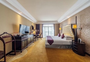 Una habitación de hotel con una cama grande, un escritorio con silla, un televisor y una ventana con cortinas.