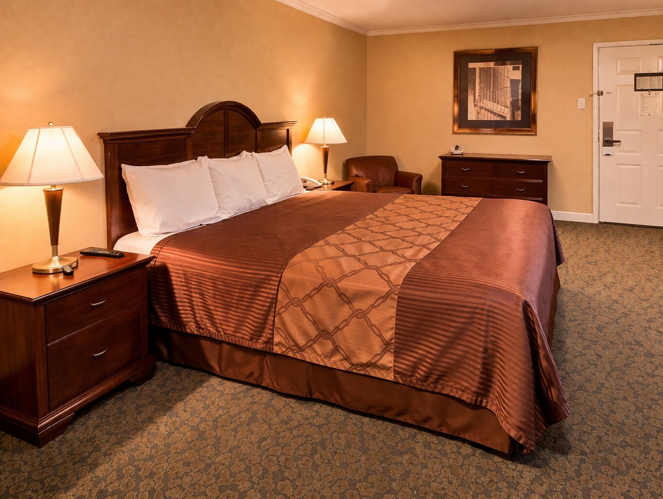 Una habitación de hotel con una cama grande, dos mesitas de noche, una silla, un escritorio y una puerta.