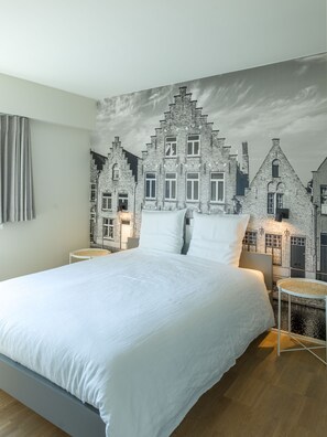 A bedroom with a large bed, a cityscape mural on the wall, and a round side table. - B&B Antares (Bruges)