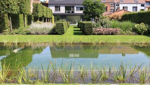 A residential building with a well-maintained garden, a pond, and a clear pathway leading to the entrance. - B&B Antares (Bruges)