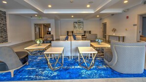 Un hall d’entrée avec des sièges, une moquette bleue et un design de plafond moderne.