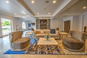 A spacious lobby with a fireplace, comfortable seating, and a large window offering a view of the outdoors.