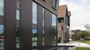 A modern building with large windows and a red flag on a pole. - Scandic Stavanger City (Stavanger)