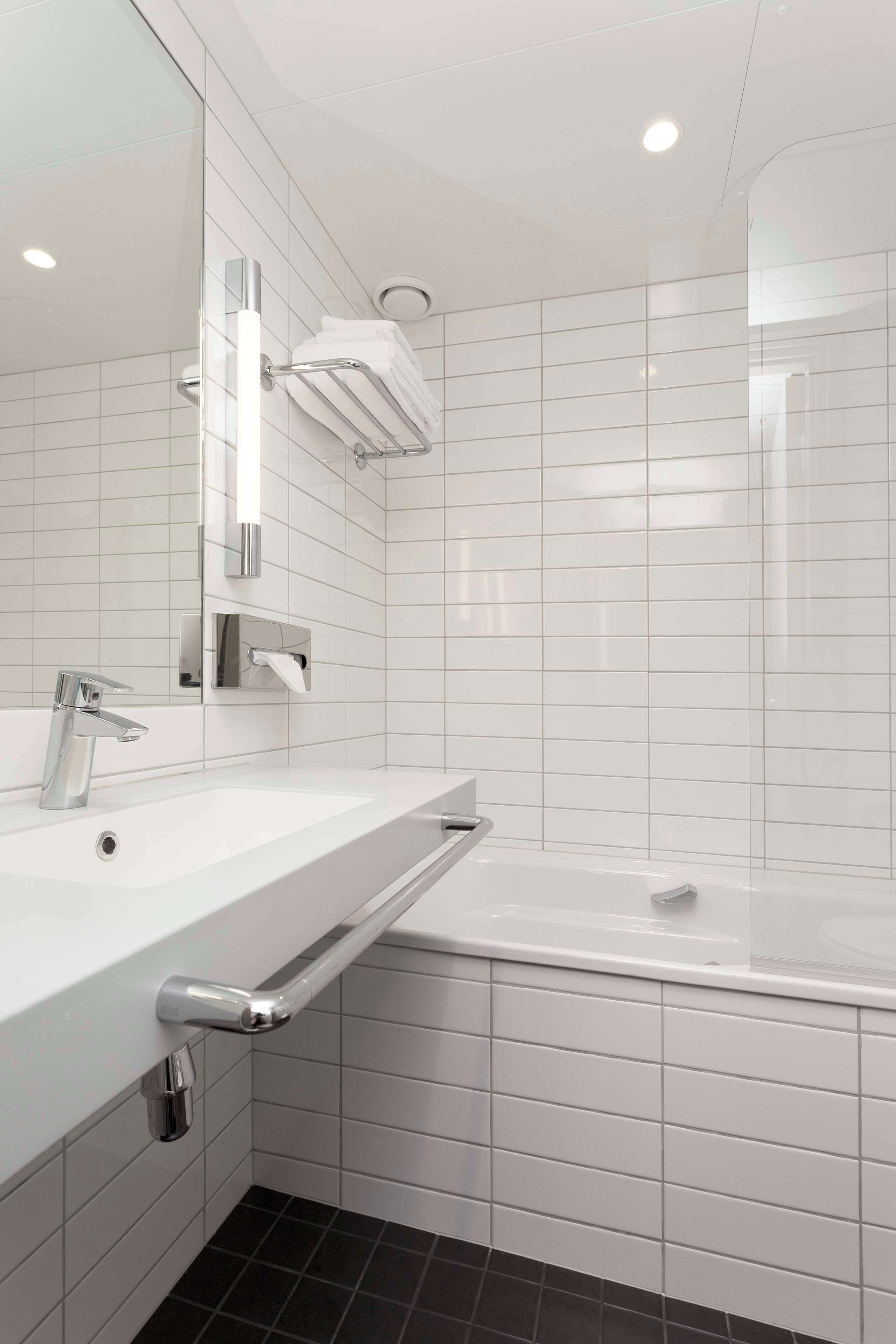 A modern bathroom with a white sink, mirror, and a glass-enclosed shower area.