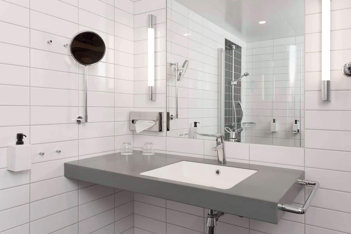 A modern bathroom with a large mirror, a sink, and a shower.