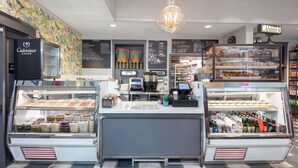 A bakery counter with a display case of pastries and a refrigerated section with beverages. - Hotel La Rose (Santa Rosa)