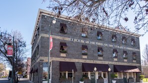 A historic building with the name "Hotel La Rose" on the facade, featuring a classic stone exterior, multiple windows with awnings, and potted plants on the ground floor.