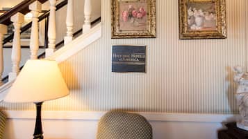 A staircase with a lamp, two framed floral paintings, and a plaque on the wall.