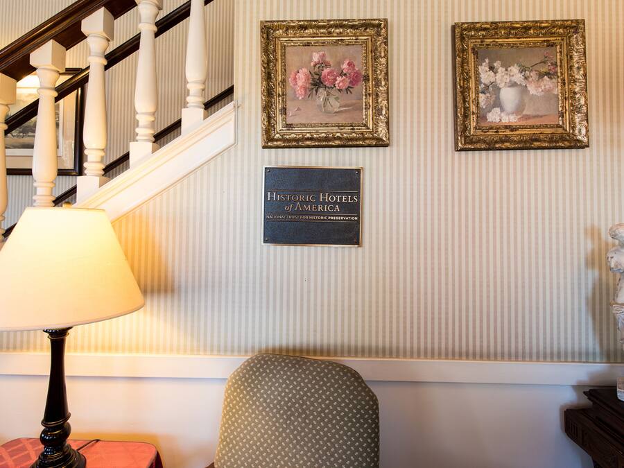 A staircase with a lamp, two framed floral paintings, and a plaque on the wall.
