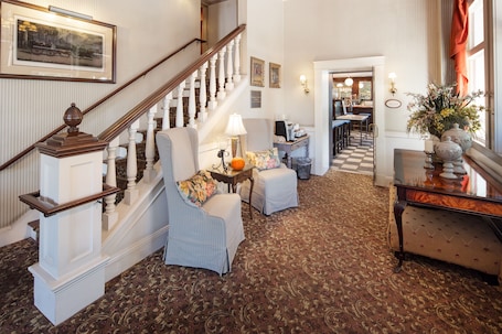 A spacious living room with a grand staircase, a dining area, and a view of the kitchen.