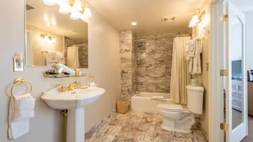 A bathroom with a marble floor, a sink, a bathtub, and a toilet.