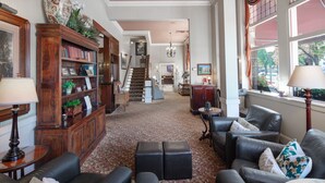 A spacious living room with a large wooden bookcase, leather sofas, and a carpeted floor. - Hotel La Rose (Santa Rosa)
