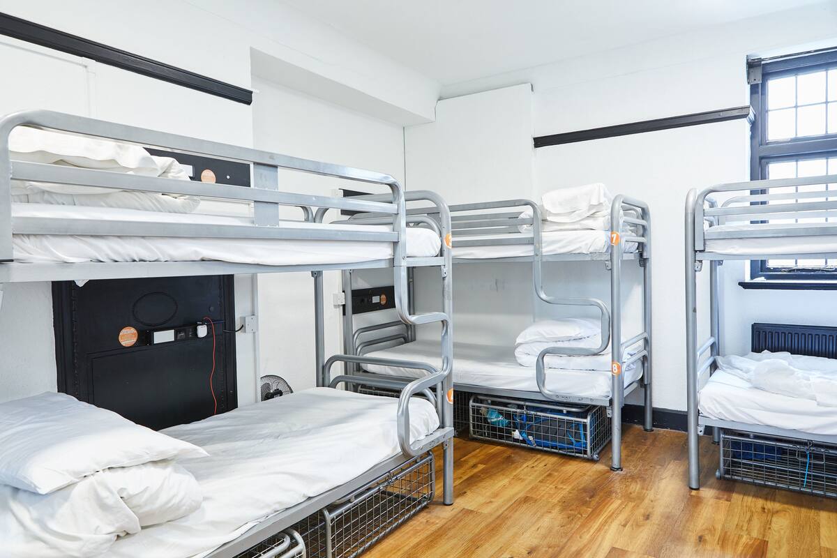 A dormitory room with bunk beds, a black door, and a window.