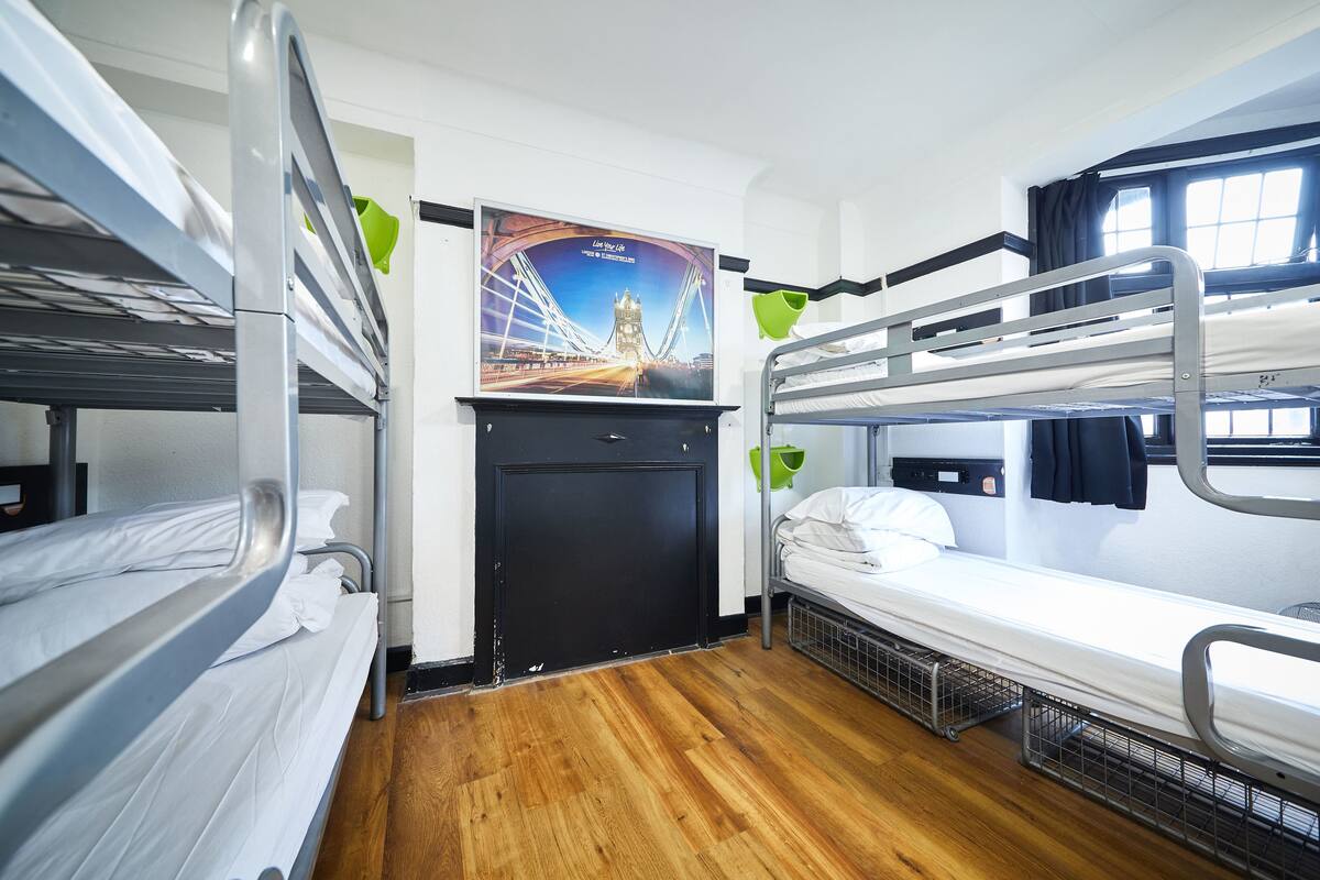 A bunk bed room with a poster of a bridge, a window with curtains, and a wooden floor.