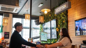 A reception area with a computer monitor, a sign labeled "RECEPTION," and a wall decorated with greenery. - St Christopher's Inn, Camden - Hostel (London)
