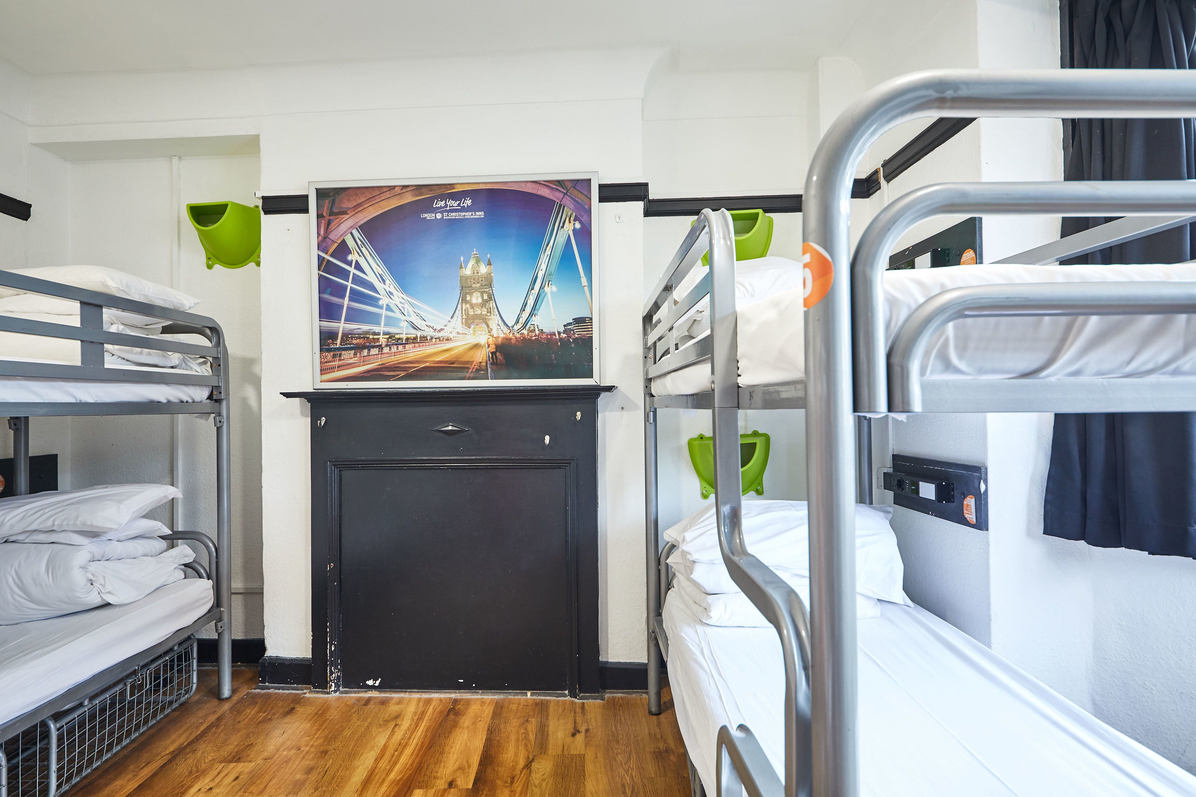 A bunk room with two beds, a black door, and a poster of a bridge.