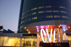 Et hotel med en moderne glasfacade og et tydeligt oplyst skilt.