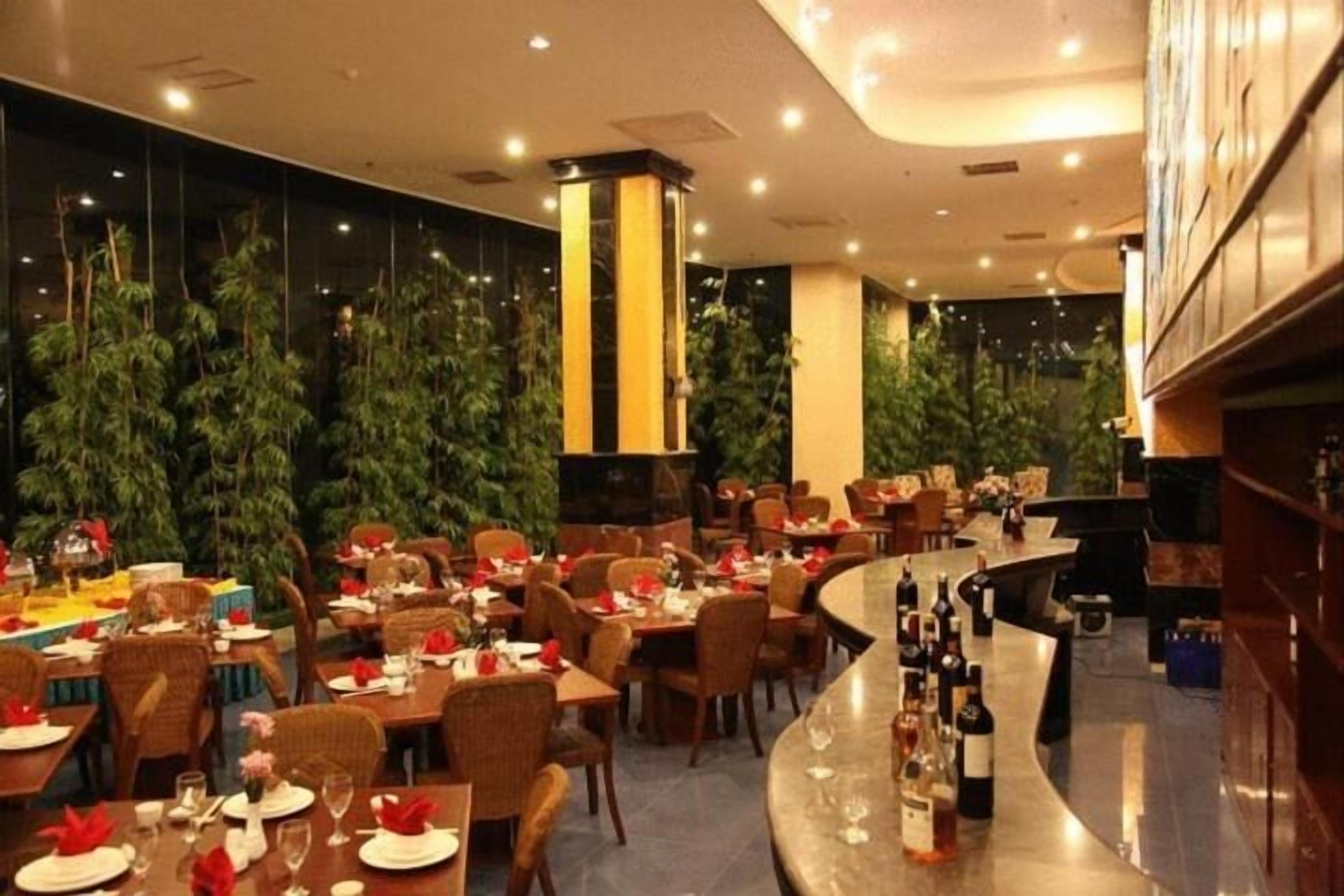 Um restaurante com várias mesas, cadeiras e um espaço de bar com garrafas.