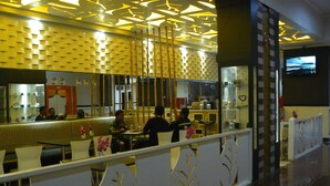 A modern restaurant with a geometric patterned ceiling, a counter with a mirror, and a seating area with a decorative partition.