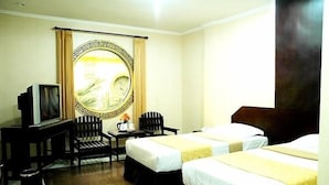 A hotel room with two beds, a television, a desk with a chair, and a large mirror with a decorative frame.