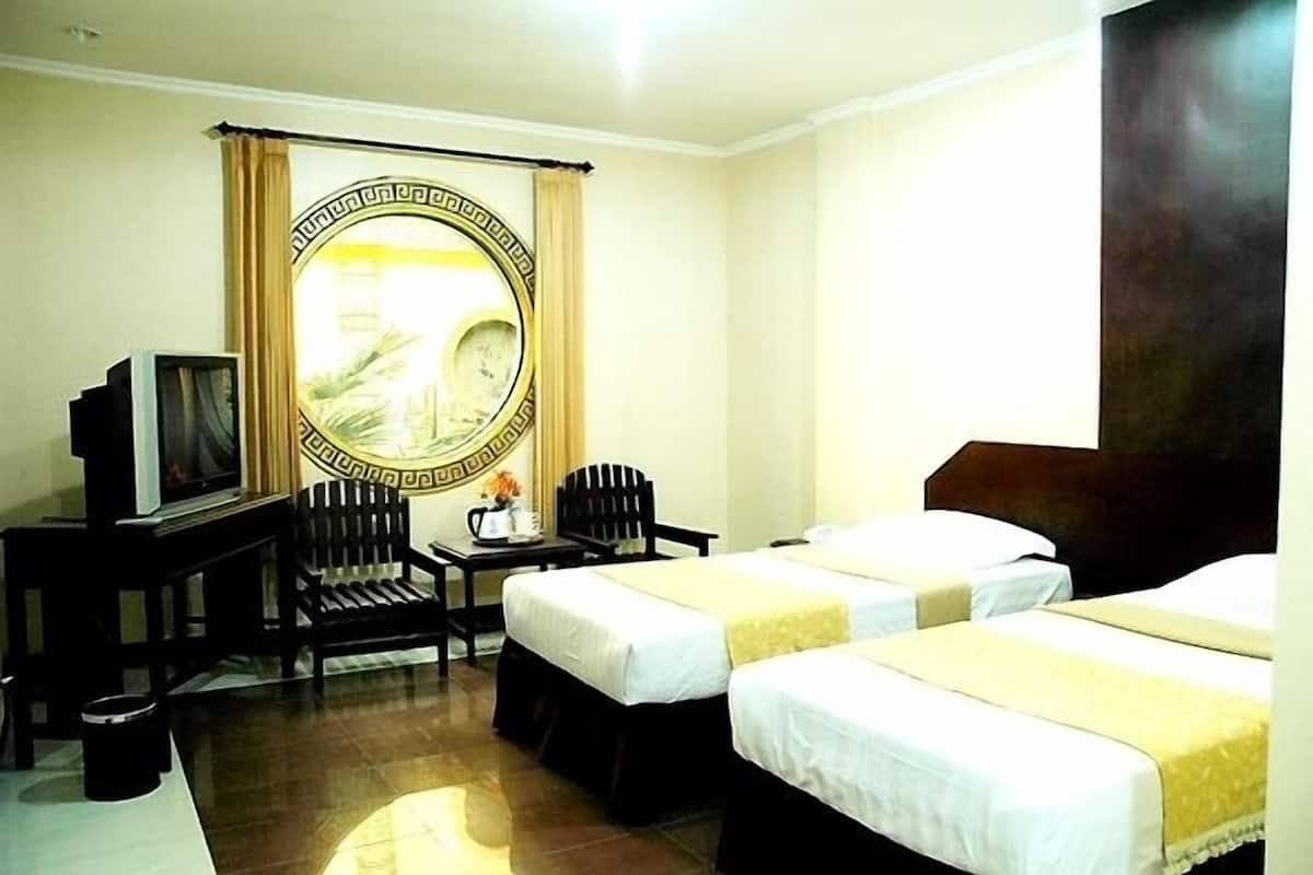 A hotel room with two beds, a television, a desk with a chair, and a large mirror with a decorative frame.