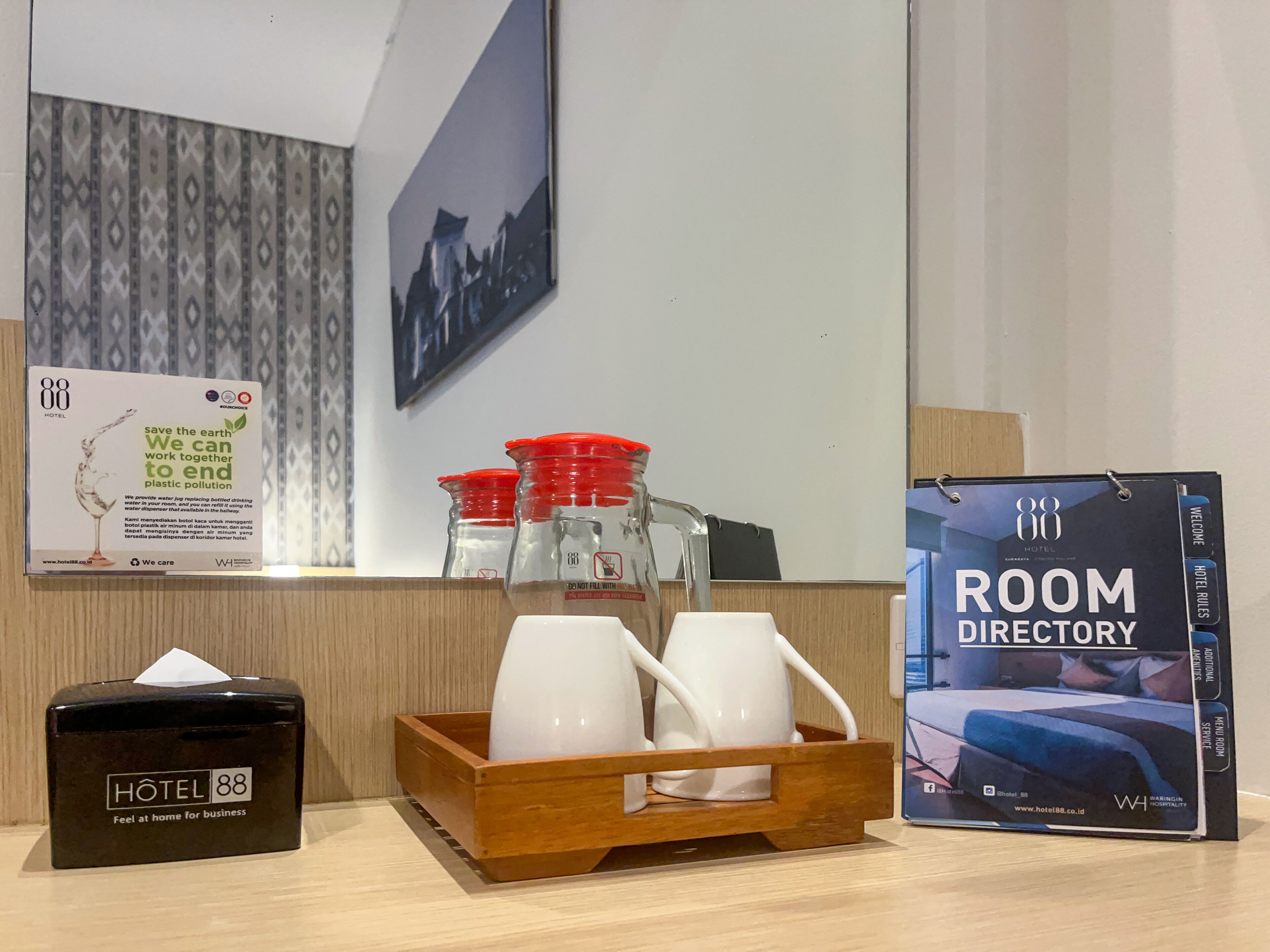 Zona de recepción de un hotel, con un directorio de habitaciones, una caja de pañuelos y un dispensador de agua.