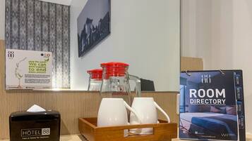 Zona de recepción de un hotel, con un directorio de habitaciones, una caja de pañuelos y un dispensador de agua.