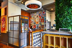 A reception area with a check-in counter, a wall decorated with various posters, and a green vertical garden.