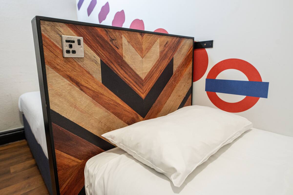 Quarto de hotel com cama, tomada e parede com um desenho circular.
