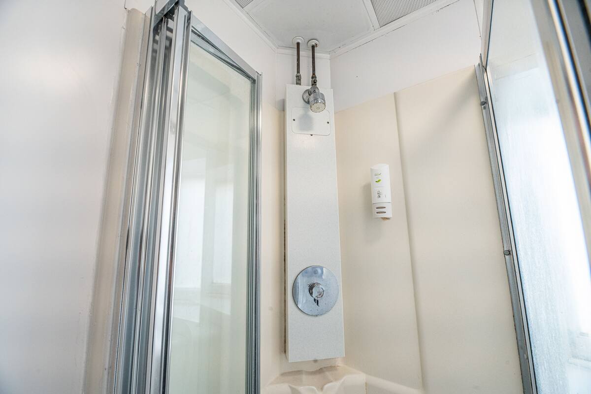 Um chuveiro com porta de vidro, painel de controle e porta-toalhas.