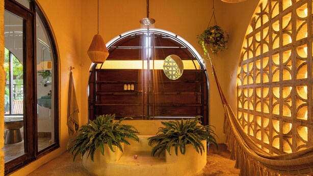 A room with a curved wooden bench, two potted plants, a hanging light fixture, and a decorative wall with a lattice pattern. - DREAMCATCHER by DW - ADULTS ONLY (San Juan)