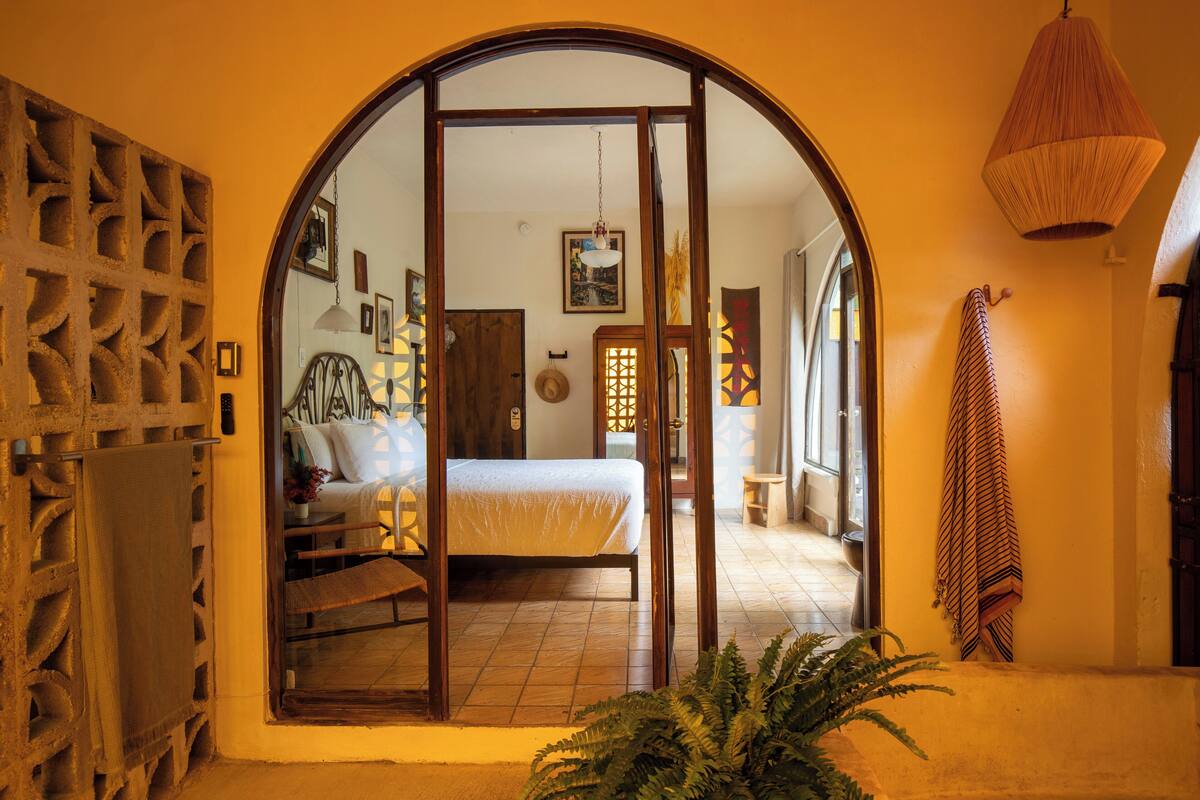 Ein Zimmer mit einem Bett, einer Holztür und einer Pendelleuchte.