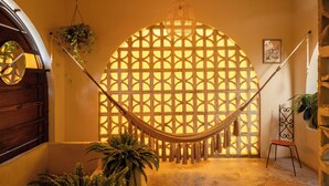 A hammock suspended between two walls with a geometric patterned window, a wooden door, and a stone wall with a plant. - DREAMCATCHER by DW - ADULTS ONLY (San Juan)