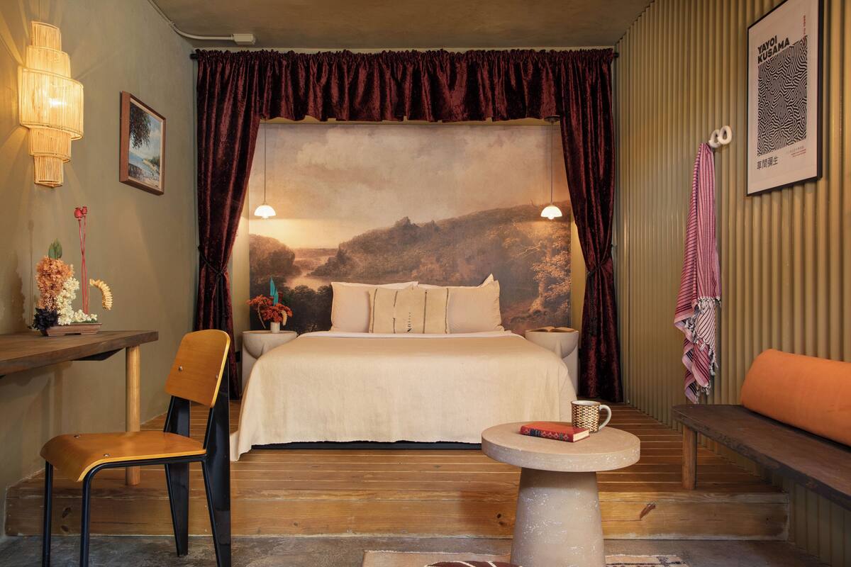 Ein Schlafzimmer mit Bett, Stuhl, Tisch und einer Bank.