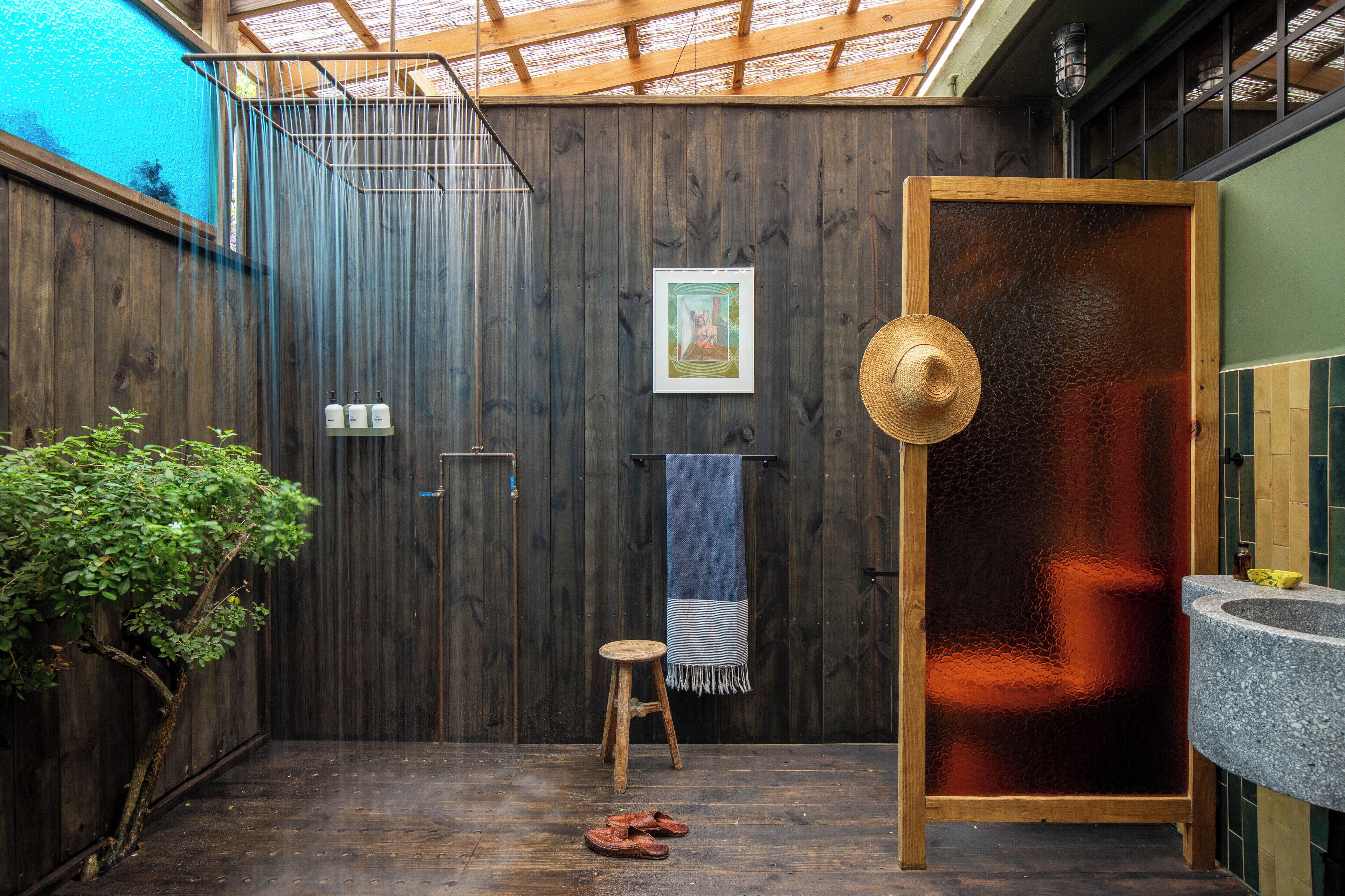 Una habitación de madera con ducha, un taburete y una toalla colgada en la pared.