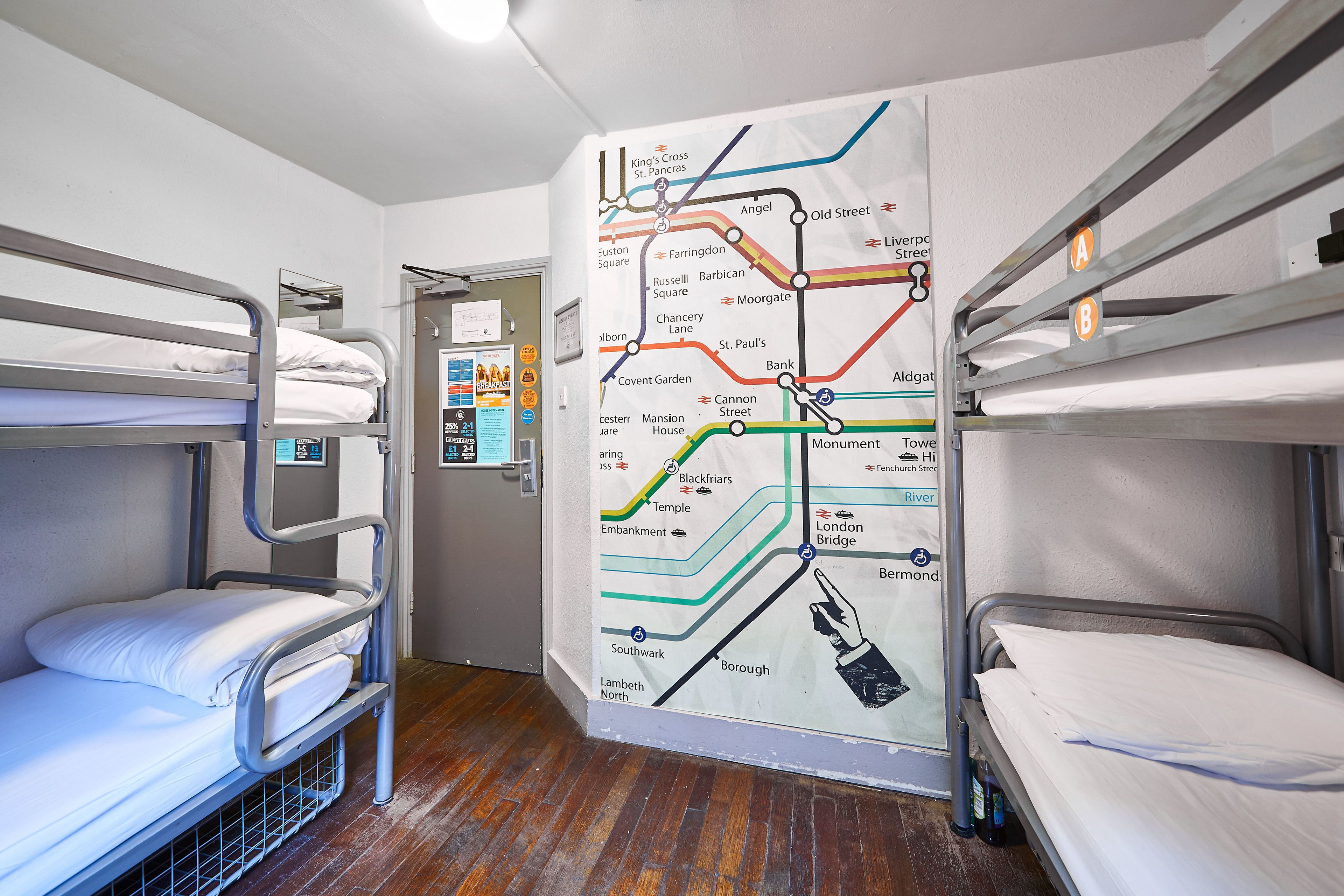 A bunk room with a map of London Underground routes on the wall, indicating various stations.