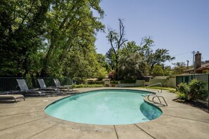 A swimming pool with lounge chairs and a fence.