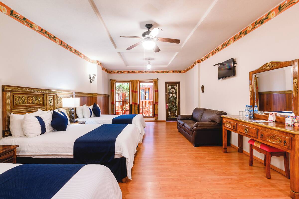 A hotel room with two beds, a desk, a chair, a ceiling fan, and a large mirror.