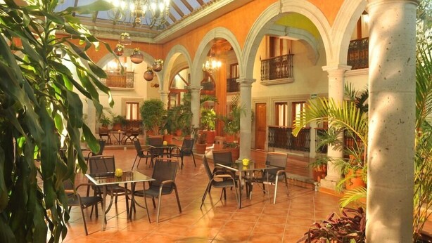 A spacious indoor courtyard with multiple seating areas, columns, and potted plants. - Mision Patzcuaro Centro Historico (Patzcuaro)