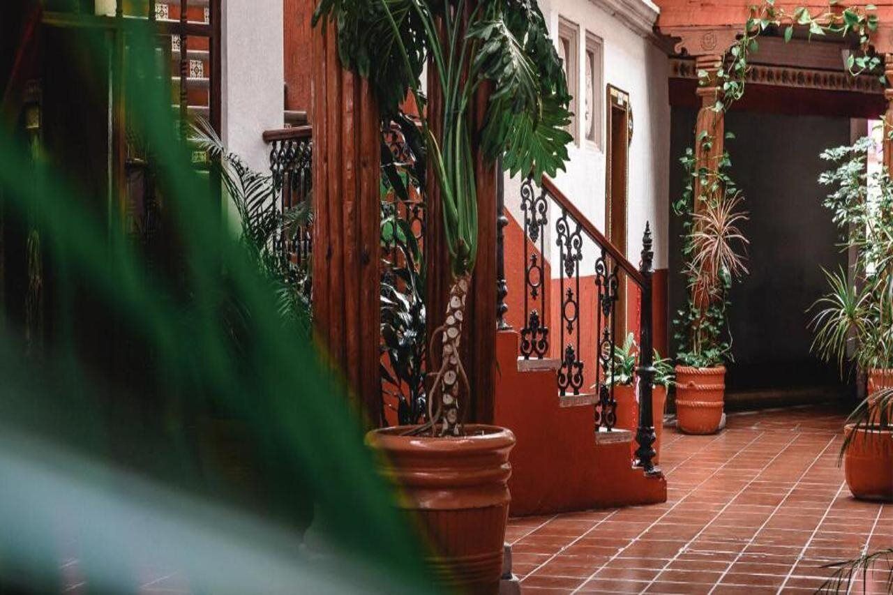 A courtyard with terracotta tiles, potted plants, and a wrought iron staircase.