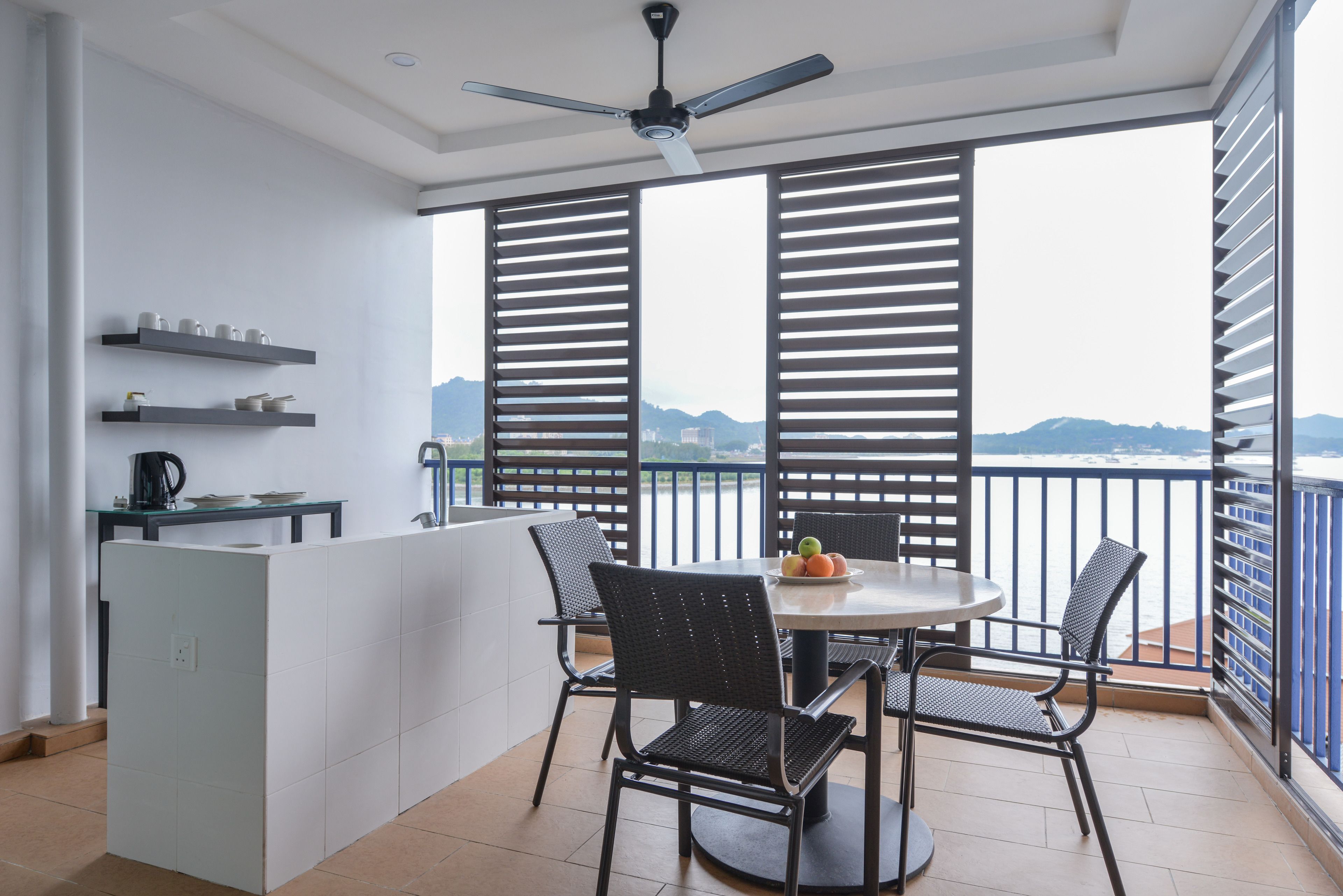 A balcony with a table and chairs, a coffee machine, and a view of the sea.