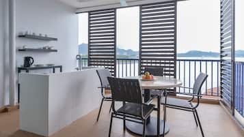 A balcony with a table and chairs, a coffee machine, and a view of the sea.